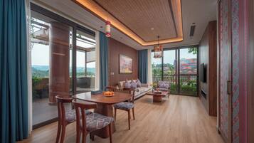 A modern living room with a wooden floor, a dining table with chairs, a sofa, and a TV mounted on the wall.