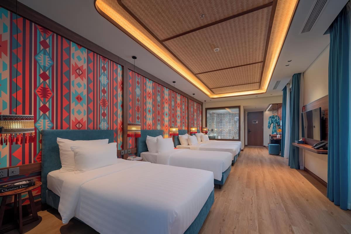 Habitación de hotel con tres camas, piso de madera y pared con diseño.