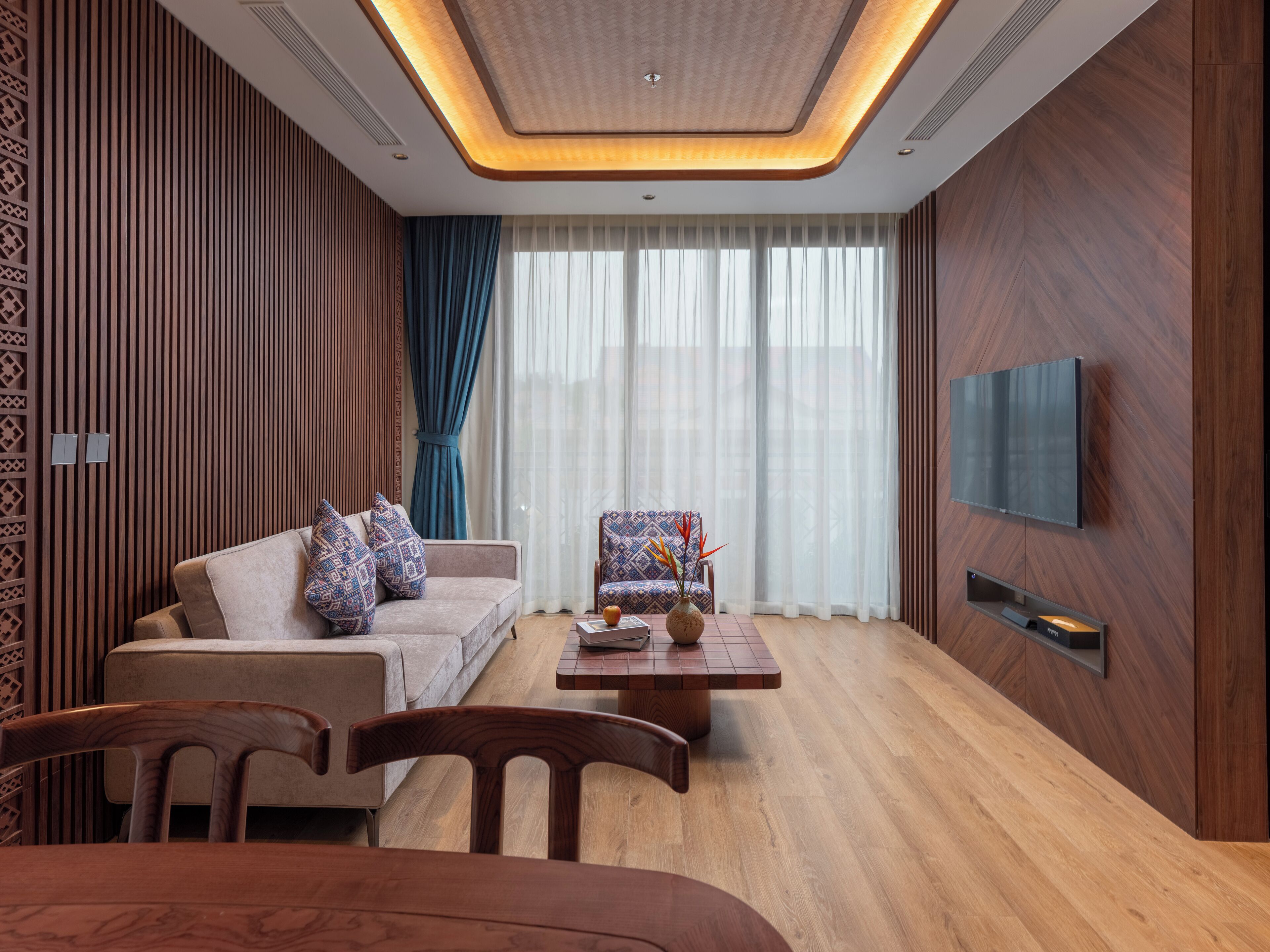 Una sala de estar moderna con un sofá, sillones, una mesa de centro y un televisor montado en la pared.
