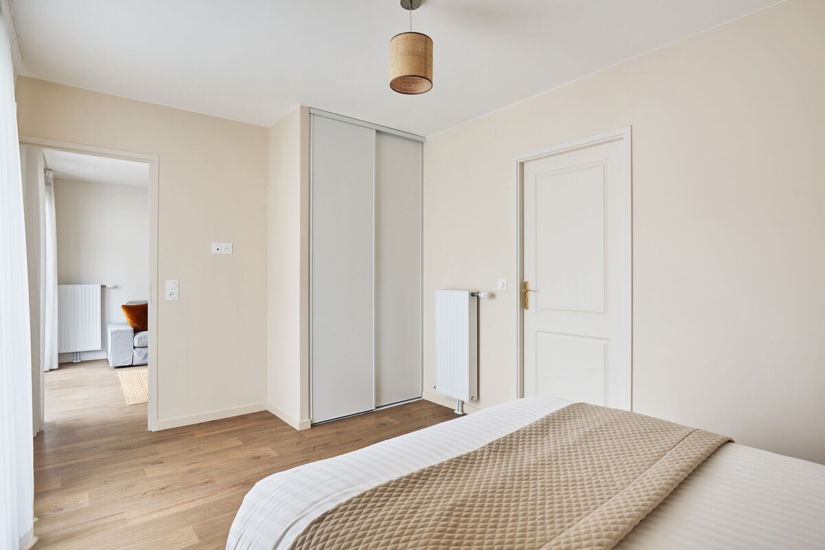 A bedroom with a bed, a wardrobe, and a door leading to another room.