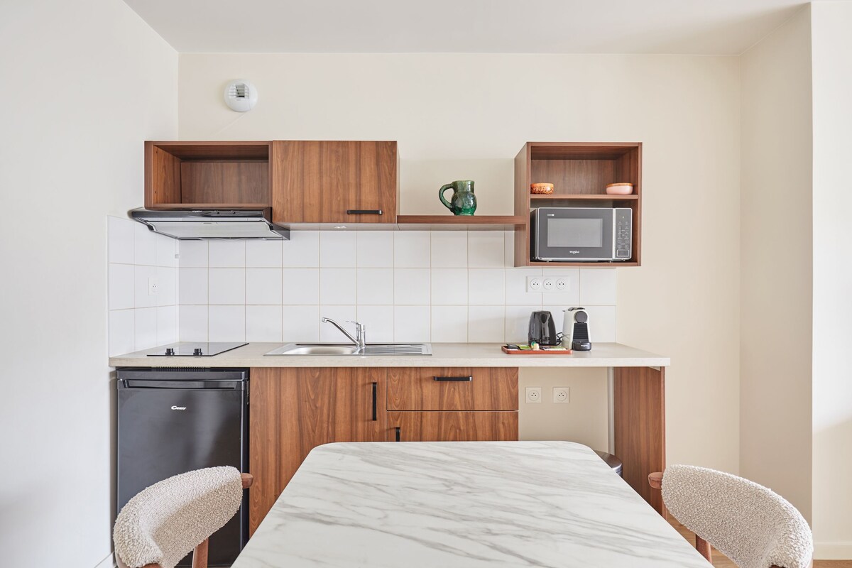 A compact kitchen with a dishwasher, microwave, and a small coffee maker on the countertop.