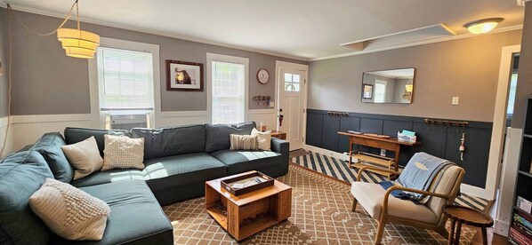 A living room with a sectional sofa, a wooden coffee table, a chair, and a small side table.