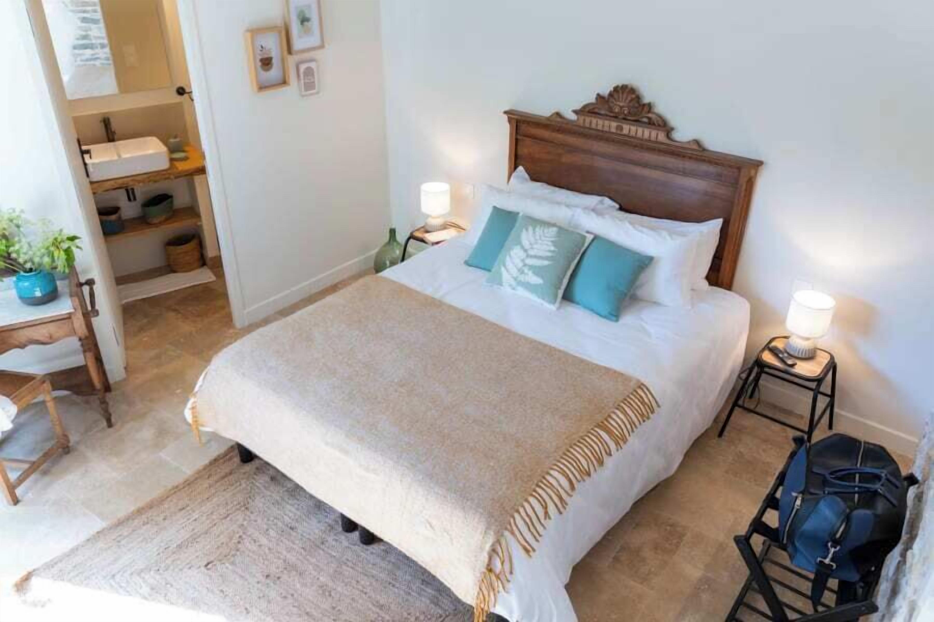 A neatly made bed with a wooden headboard, two bedside lamps, and a bedside table with a lamp.