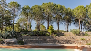 A pool area with a wooden deck, stone steps, and a stone wall. - Les Terres Aoyama (Saint-Julien-les-Rosiers)