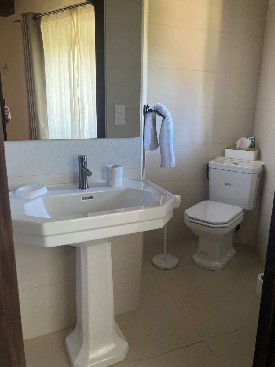 Ein Badezimmer mit einem Standwaschbecken, einer Toilette und einem Spiegel über dem Waschbecken.