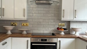 Una cocina moderna con armarios blancos, horno de acero inoxidable y encimera de madera.