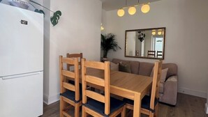 Un espacio habitable compacto con una mesa de comedor, sillas, un sofá, un espejo y un refrigerador.