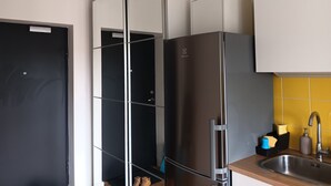 Een keuken met een zwarte, een zilveren en een witte koelkast. Er is een spoelbak met een kraan en een zeepdispenser.