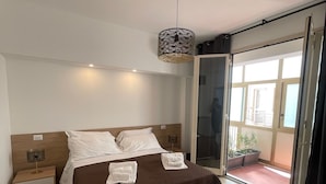 A bedroom with a bed, a nightstand, a lamp, and a view of the outside through a sliding door. - Corso Italia 72 (Catania)