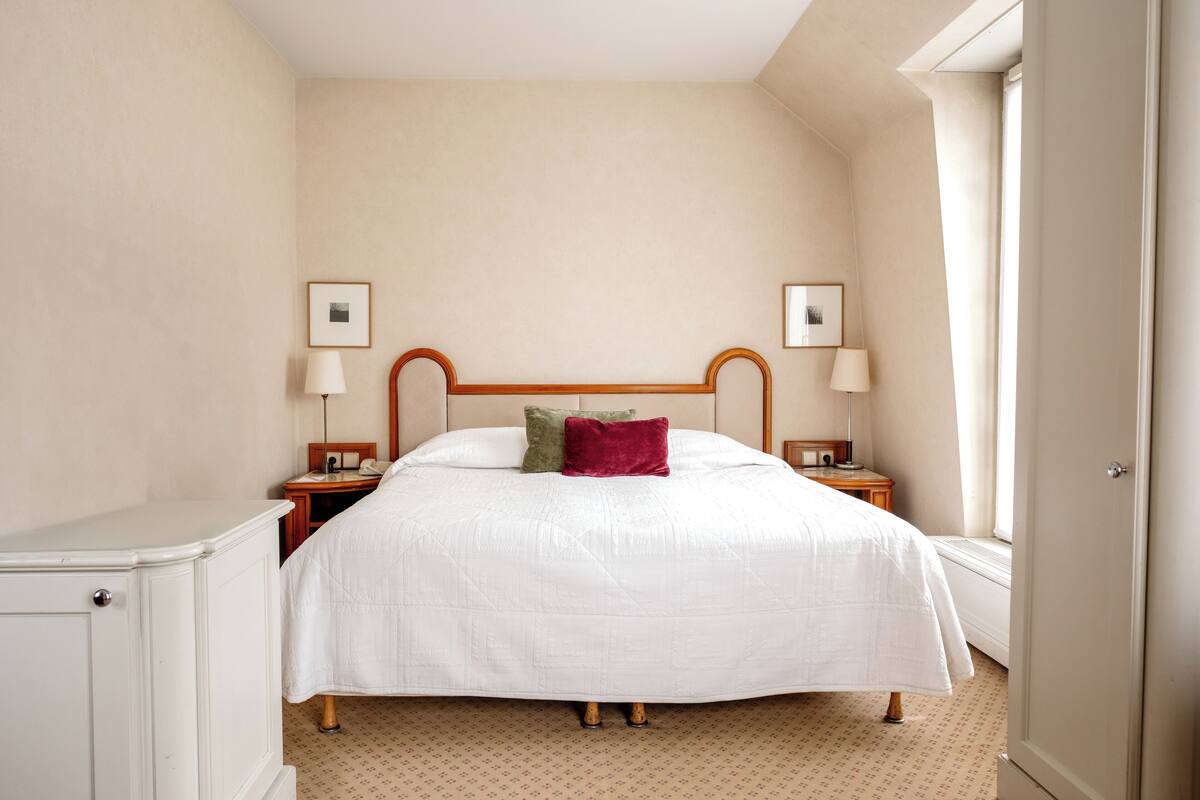 A neatly arranged bedroom with a large bed, two bedside tables, and a nightstand.