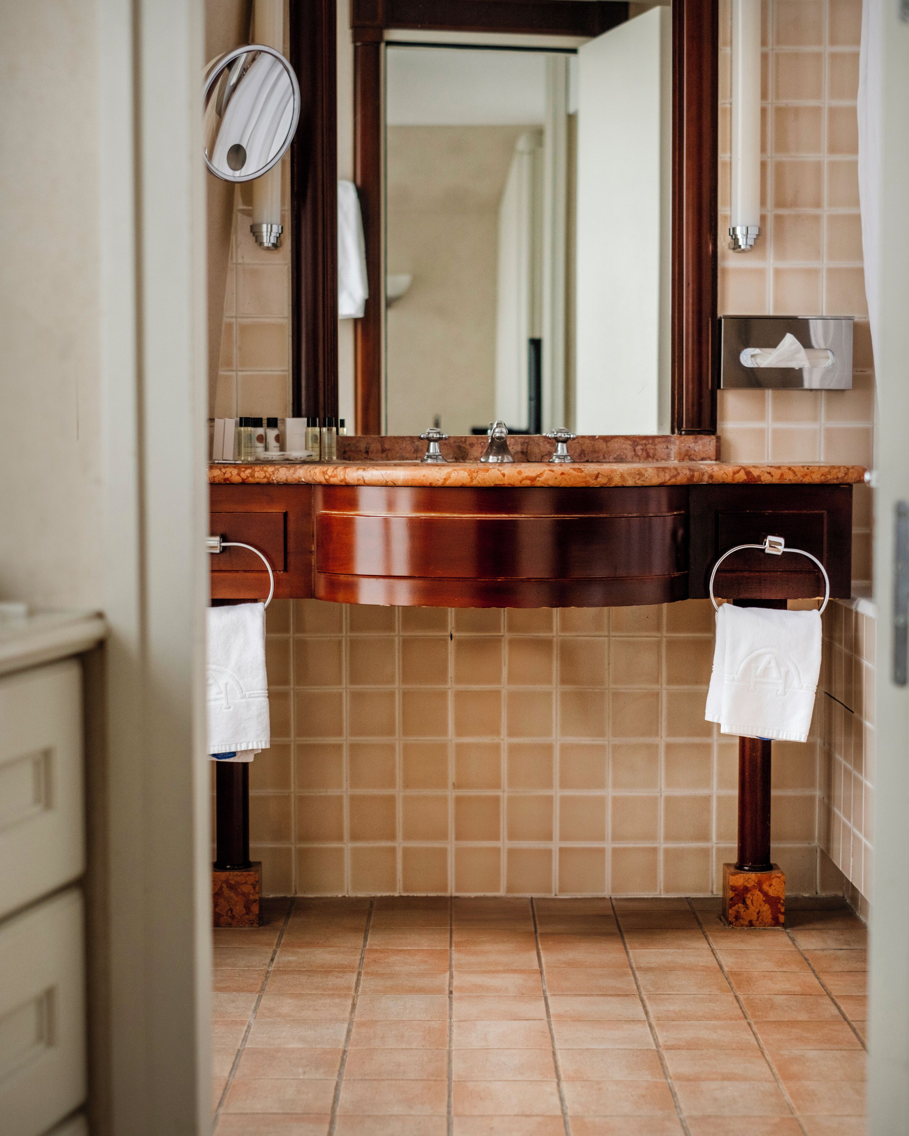 A bathroom with a marble countertop, a sink, a mirror, and a towel rack.