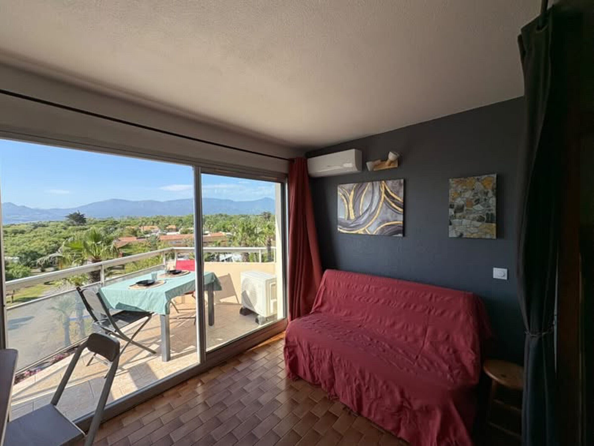 Una stanza con un balcone, un letto e opere d'arte alle pareti.
