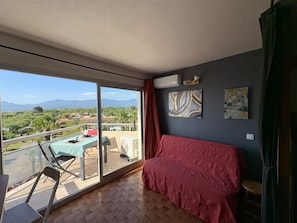 Una habitación con balcón, una cama y obras de arte en la pared.