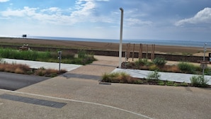 A coastal pathway with a metal pole, a bench, and a sign indicating 'Centre-ville'.