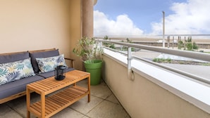 A balcony with a sofa, a wooden table, and a green plant.