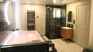Ein modernes Badezimmer mit einer großen Badewanne, einer Duschkabine aus Glas und einem Waschtisch mit Spiegel.