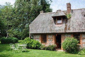 A thatched-roof cottage with a stone facade, a small window, and a door. - Cottage Les Forières (Saint-Honoré)