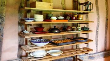 A rustic wooden shelf with various kitchenware and utensils.