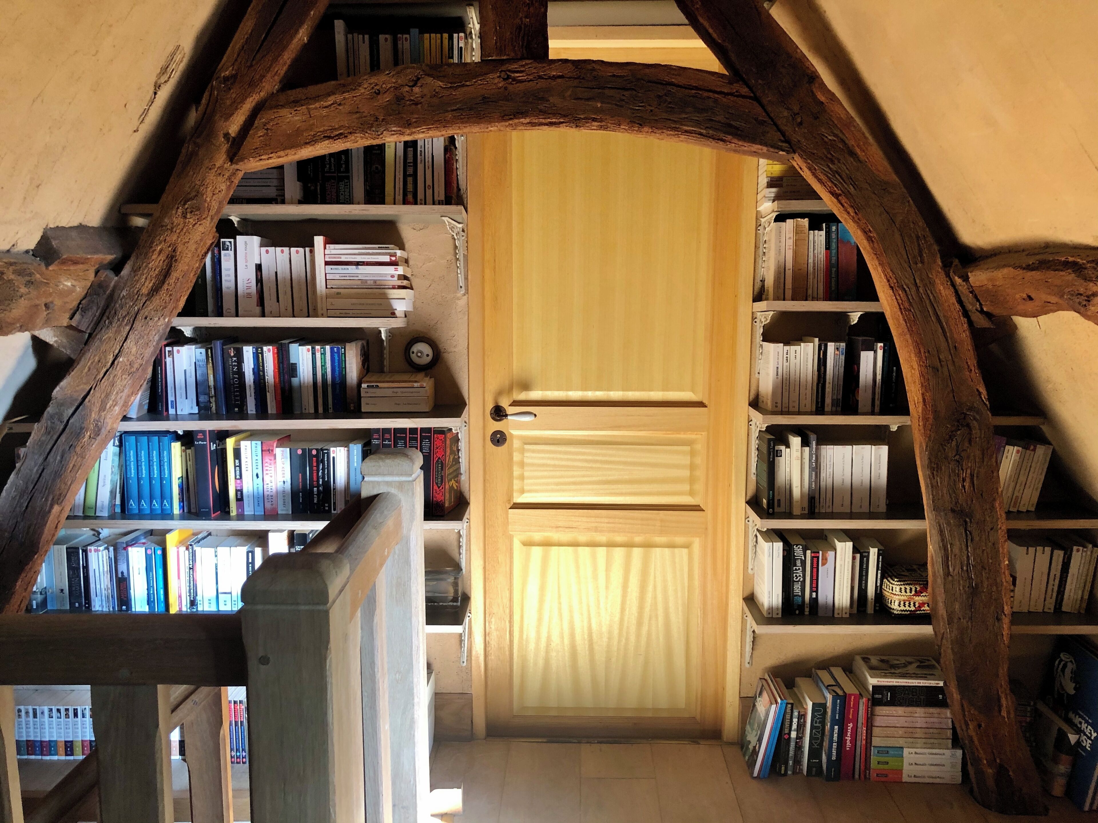 A wooden bookshelf filled with books, a door, and a wooden archway.