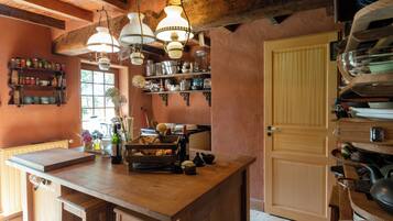 Una cocina rústica con mostradores de madera, lámparas colgantes y estantes con utensilios de cocina.