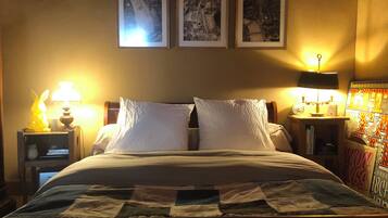 A hotel room with a bed, two bedside tables with lamps, and three framed pictures on the wall.