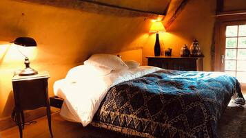 A cozy bedroom with a bed, a nightstand, a lamp, and a window.