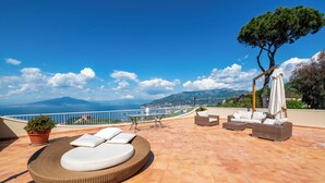 Une terrasse sur le toit aménagée avec un canapé en osier, une table à manger et du mobilier d’extérieur.
