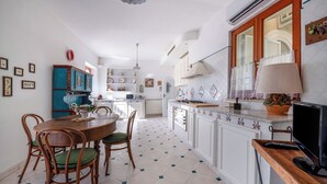 Une cuisine spacieuse avec un coin repas, dotée d’un sol carrelé, de meubles en bois et d’une cuisinière moderne.