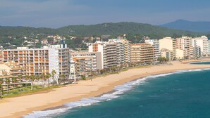 Un paysage urbain côtier avec de hauts immeubles, une plage de sable et une vue sur l’océan.