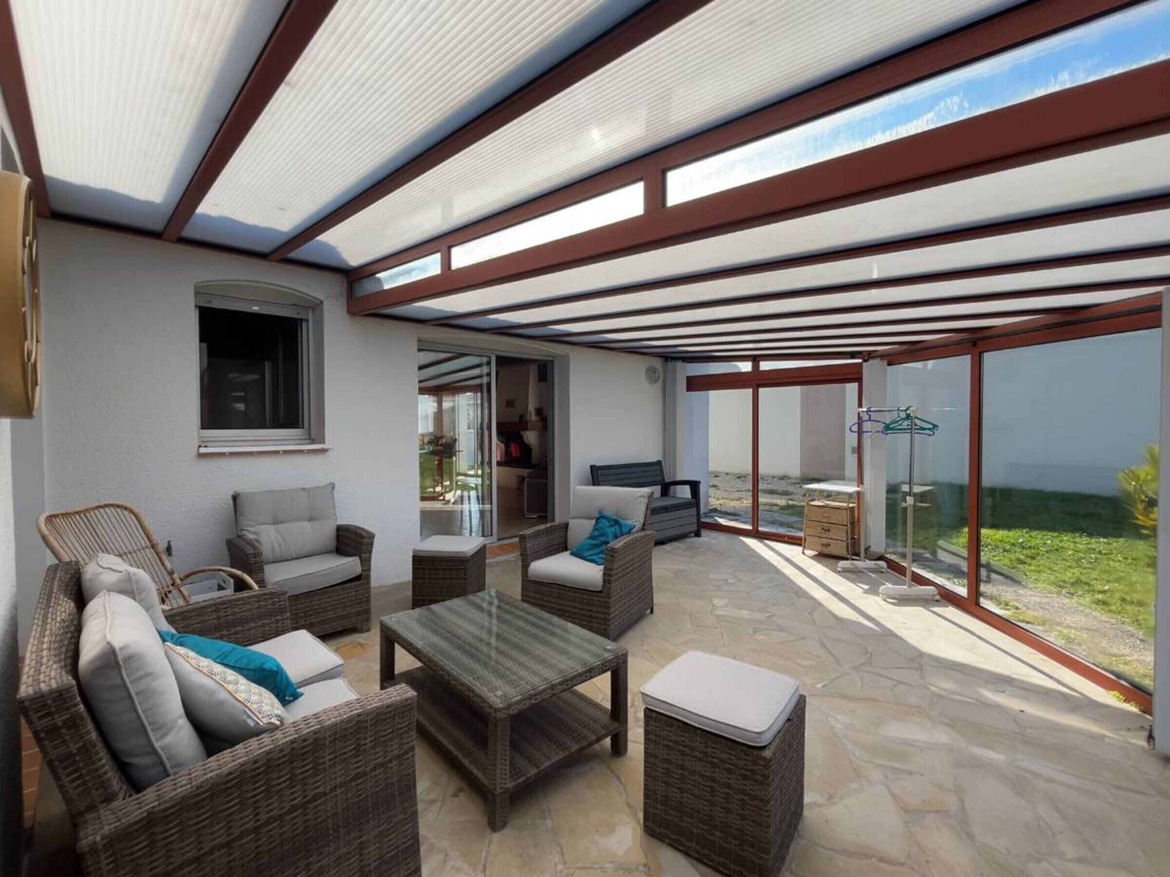A covered patio area with wicker furniture, a table, and a view of the outdoors.