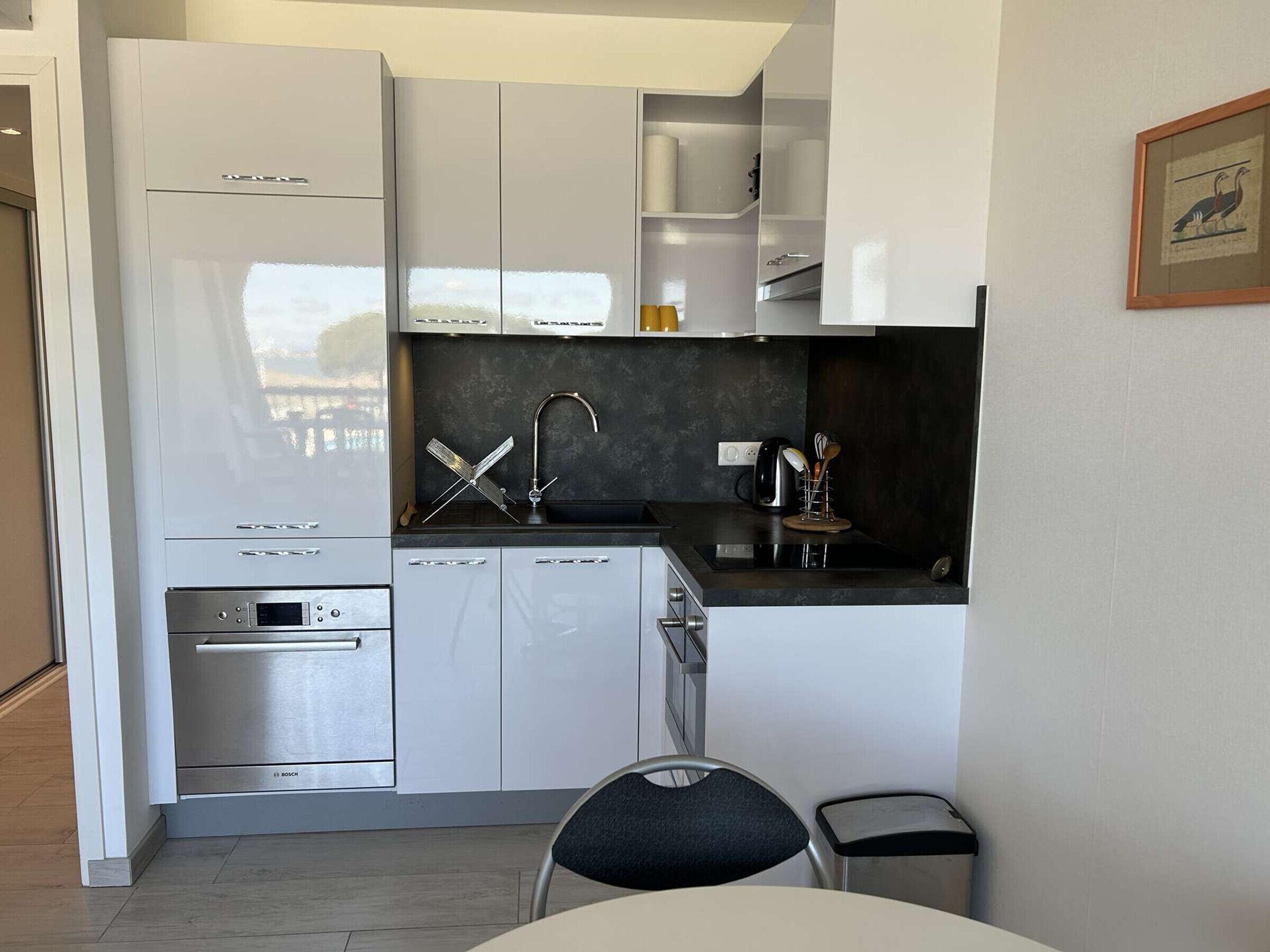 A modern kitchen with white cabinets, a Bosch oven, and a sink with a faucet.