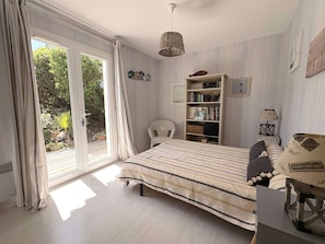 Un dormitorio con cama, estantería, silla y escritorio.