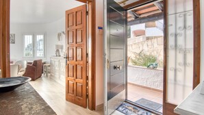 A room with a wooden door, a sliding glass door leading to a balcony, a dining area with a table and chairs, and a view of the outside. - Modern House on the Costa Brava with Private Pool and Air Conditioning (Calonge)