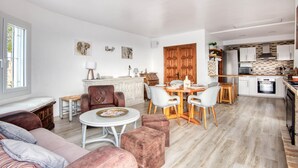 A spacious living area with a dining table, sofas, and a kitchen in the background. - Modern House on the Costa Brava with Private Pool and Air Conditioning (Calonge)