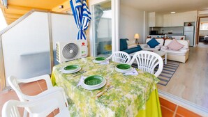 A dining area with a table set for four, white chairs, and a fan.
