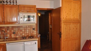 Une cuisine compacte dotée de meubles en bois, d’un four à micro-ondes, d’un lave-vaisselle et d’un dosseret carrelé.