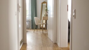Un pasillo con piso de madera que conduce a una habitación con escritorio, silla y espejo.