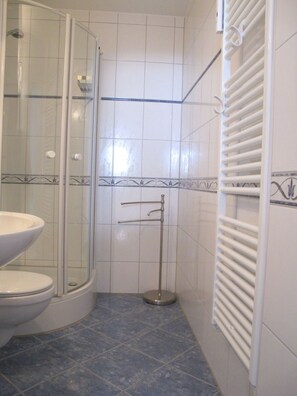 A bathroom with a glass shower enclosure, a white sink, and a towel rack. - Welcome to Hanseat I, Apartment 63—your elegant vacation home in Grömitz! (Grömitz)