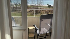 Un balcón con vista al mar y una silla.