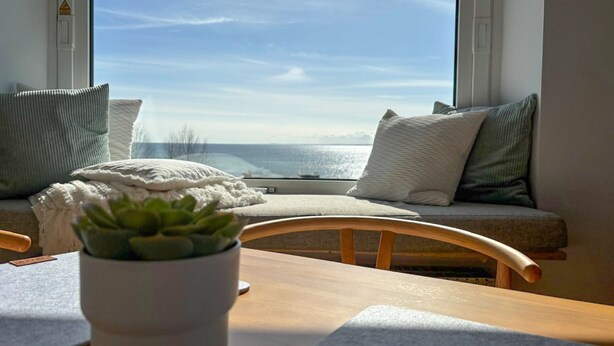 Un rincón acogedor con vistas al mar, una mesa de madera y una planta en maceta.