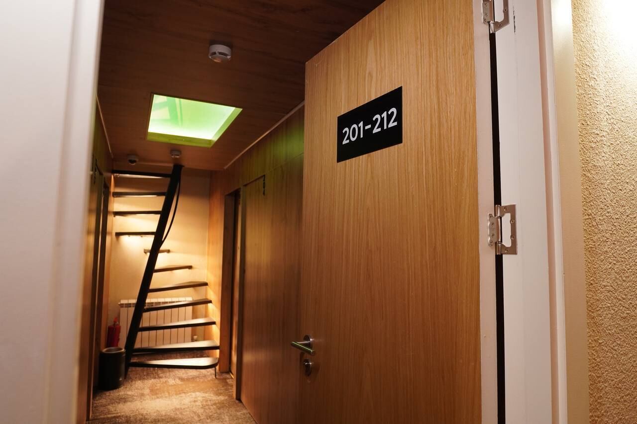 A wooden door with a sign reading "201-212" and a skylight above a staircase.