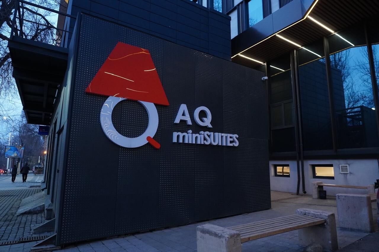 Un bâtiment doté d’un grand panneau numérique affichant le logo et le nom « AQ miniSUITES ».