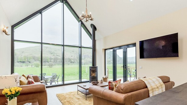 A spacious living room with large windows, a fireplace, and a flat-screen TV.