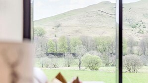 A view through a window of a green landscape with hills and trees.