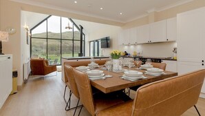 A modern kitchen with white cabinets, a dining table set for six, and a large window offering a view of the outdoors.