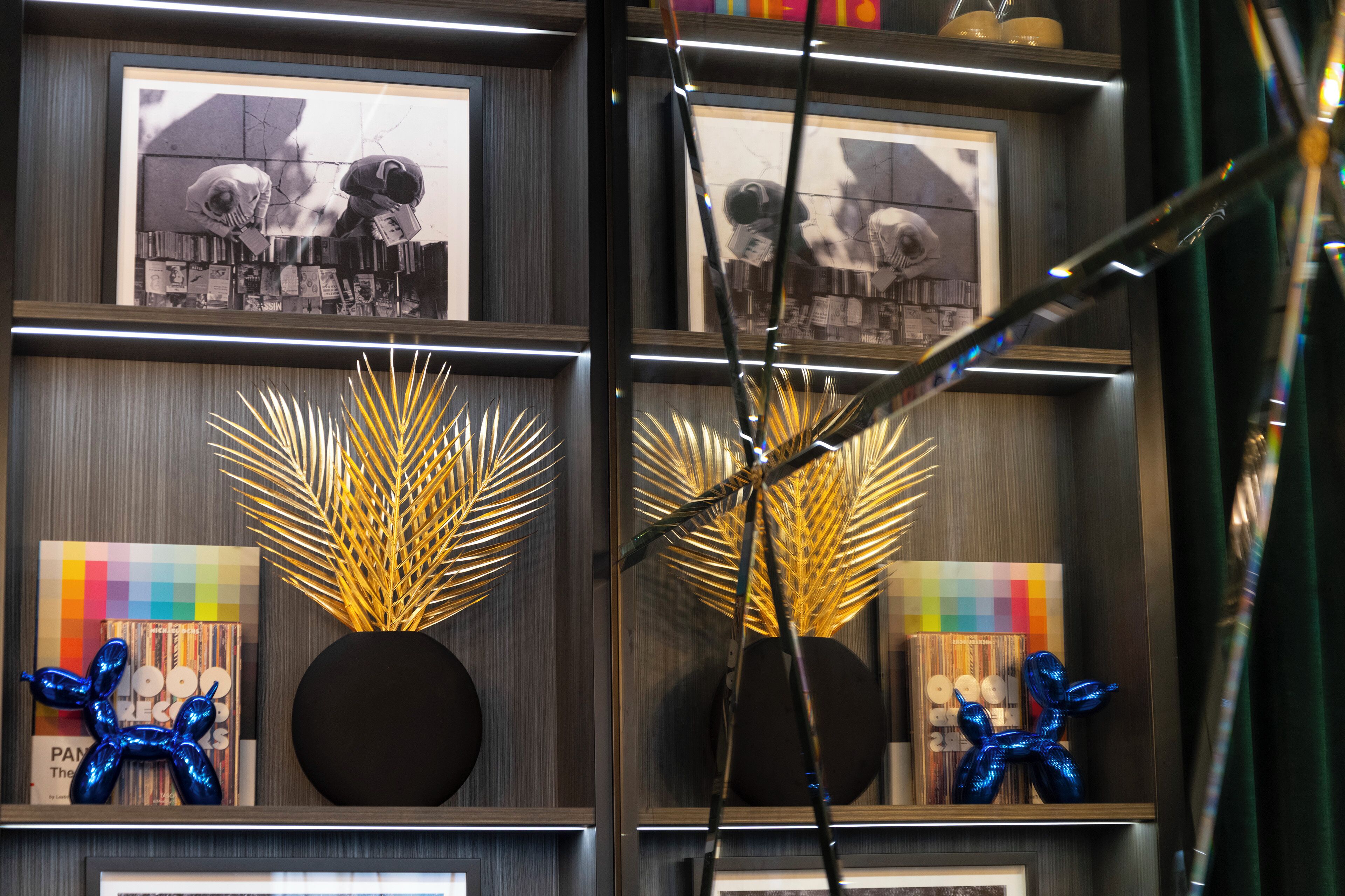 A wall with framed photographs, decorative golden plants, and blue balloon sculptures.