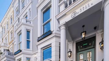 Un edificio histórico con fachada clásica, una entrada destacada con puerta verde y un cartel que indica que es un hotel.