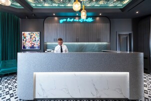 Una reception con un bancone in marmo, un neon sopra e un grande quadro astratto appeso alla parete.