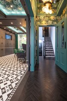 Eine Hotelhalle mit Schachbrettmuster-Boden, einer Treppe und einer Sitzecke mit Stühlen.