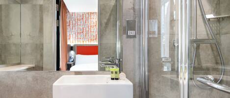 Une salle de bain moderne avec une douche à parois de verre, un lavabo blanc et un miroir.